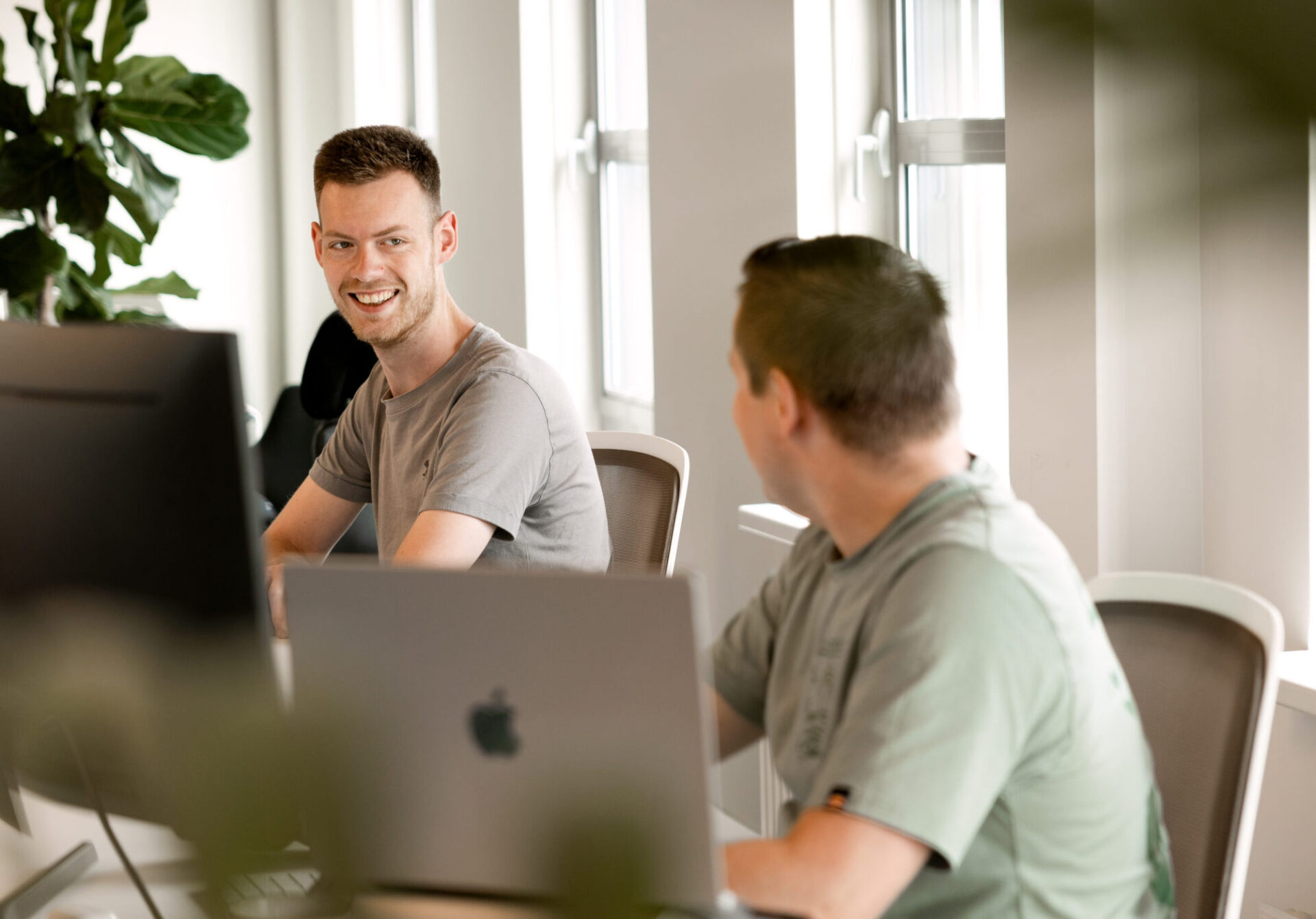 Twee developers van Moddit overleggen achter hun schermen op kantoor
