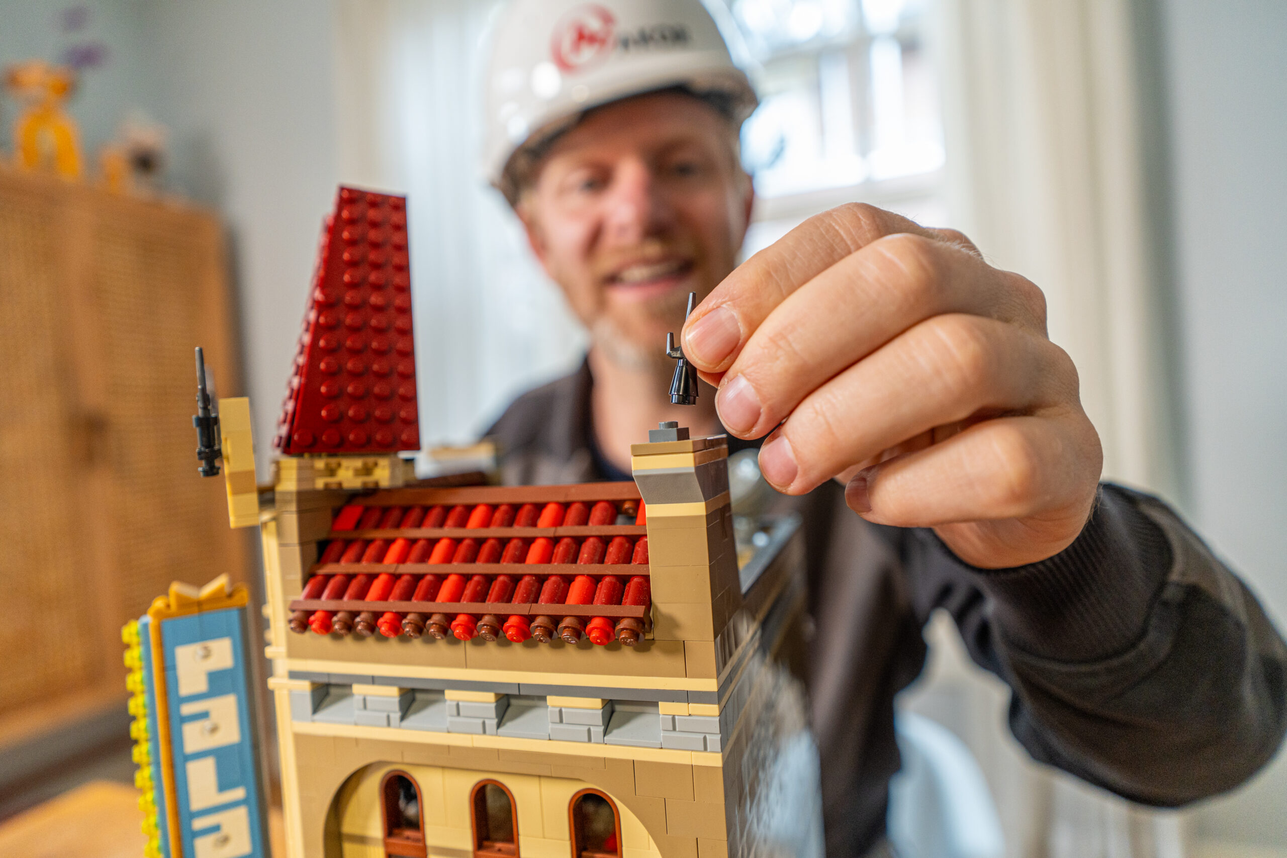 AKOR-medewerker plaatst een blokje op een miniatuurgebouw