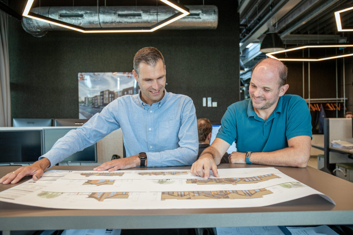 Twee mannen bekijken een bouwtekening op tafel