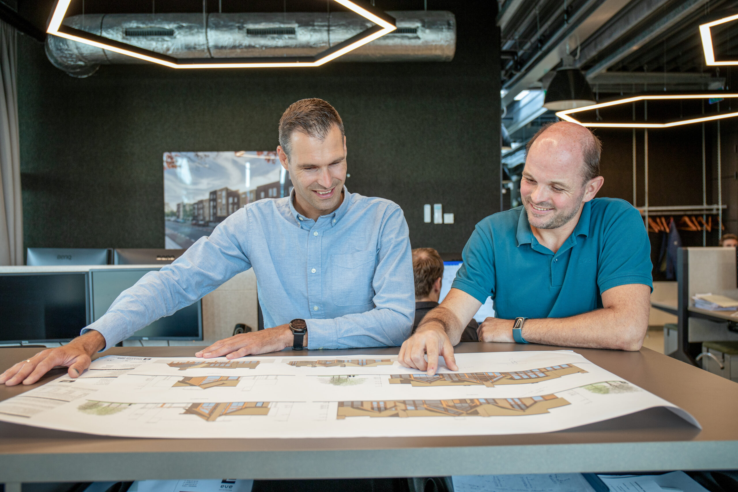 Twee mannen bekijken een bouwtekening op tafel